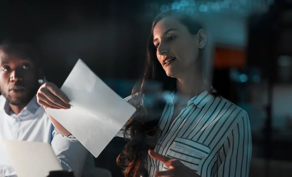 Businesswoman presenting a document during a team meeting in a modern office, discussing ideas with colleagues in a professional workplace setting.