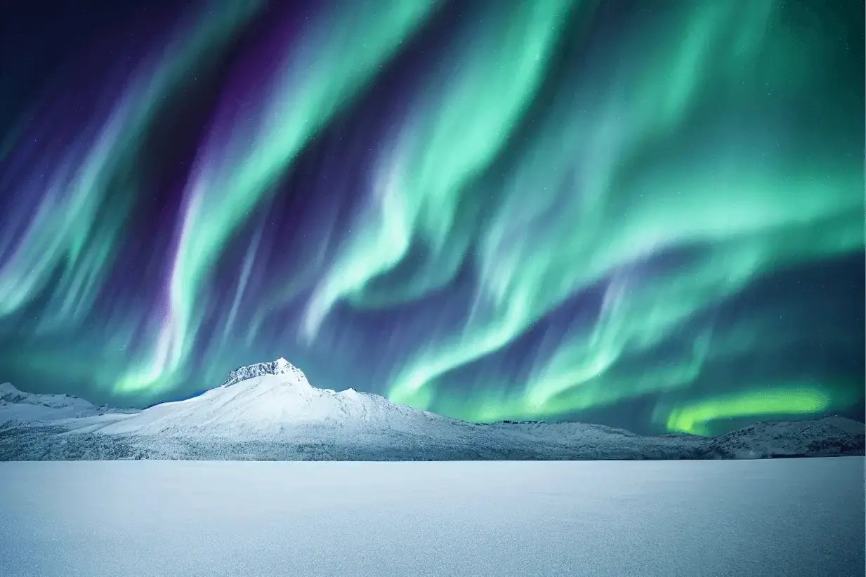 Northern lights sweeping across a night sky in shades of green and blue above a snow-covered mountain and frozen landscape.
