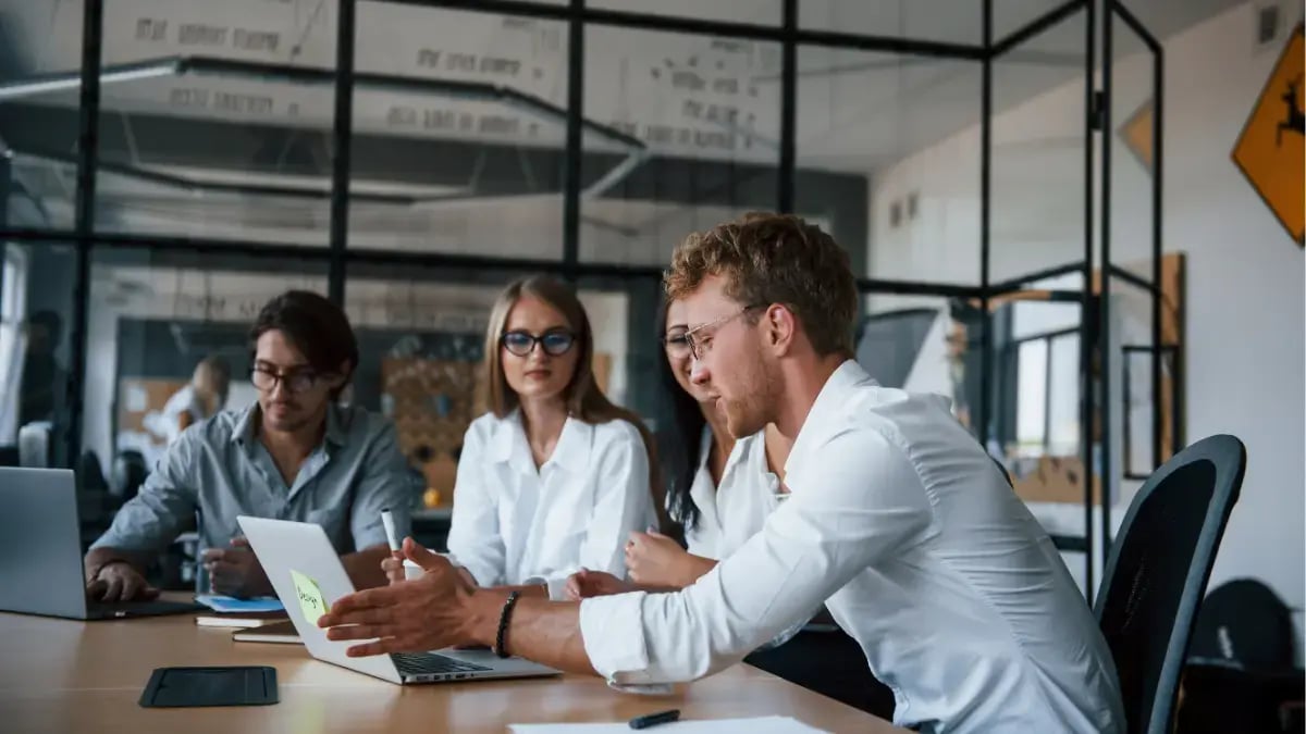 Business team collaborating in a modern office meeting while reviewing a laptop during a project discussion.